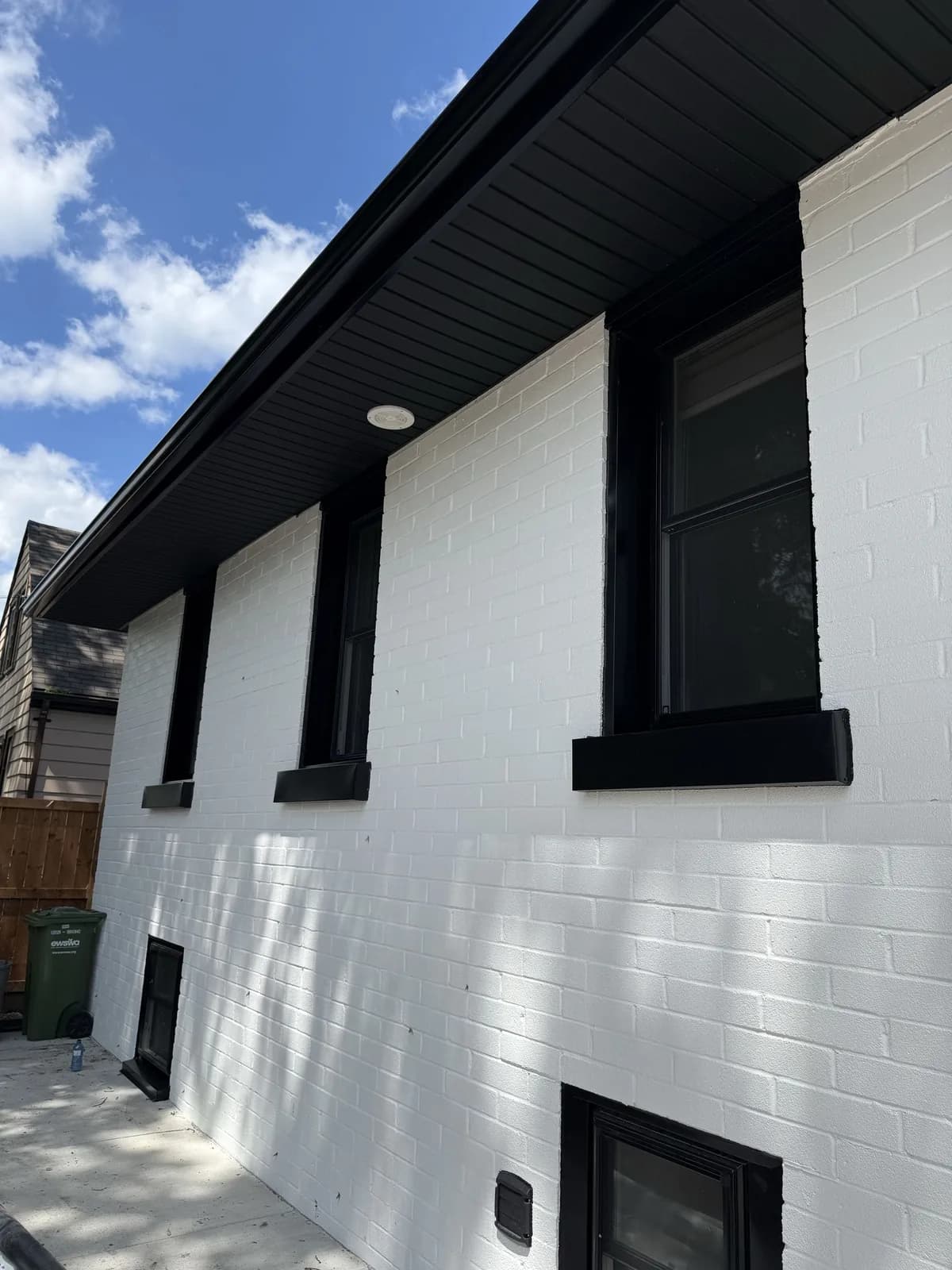 Dark soffit and fascia above black-framed windows on white brick