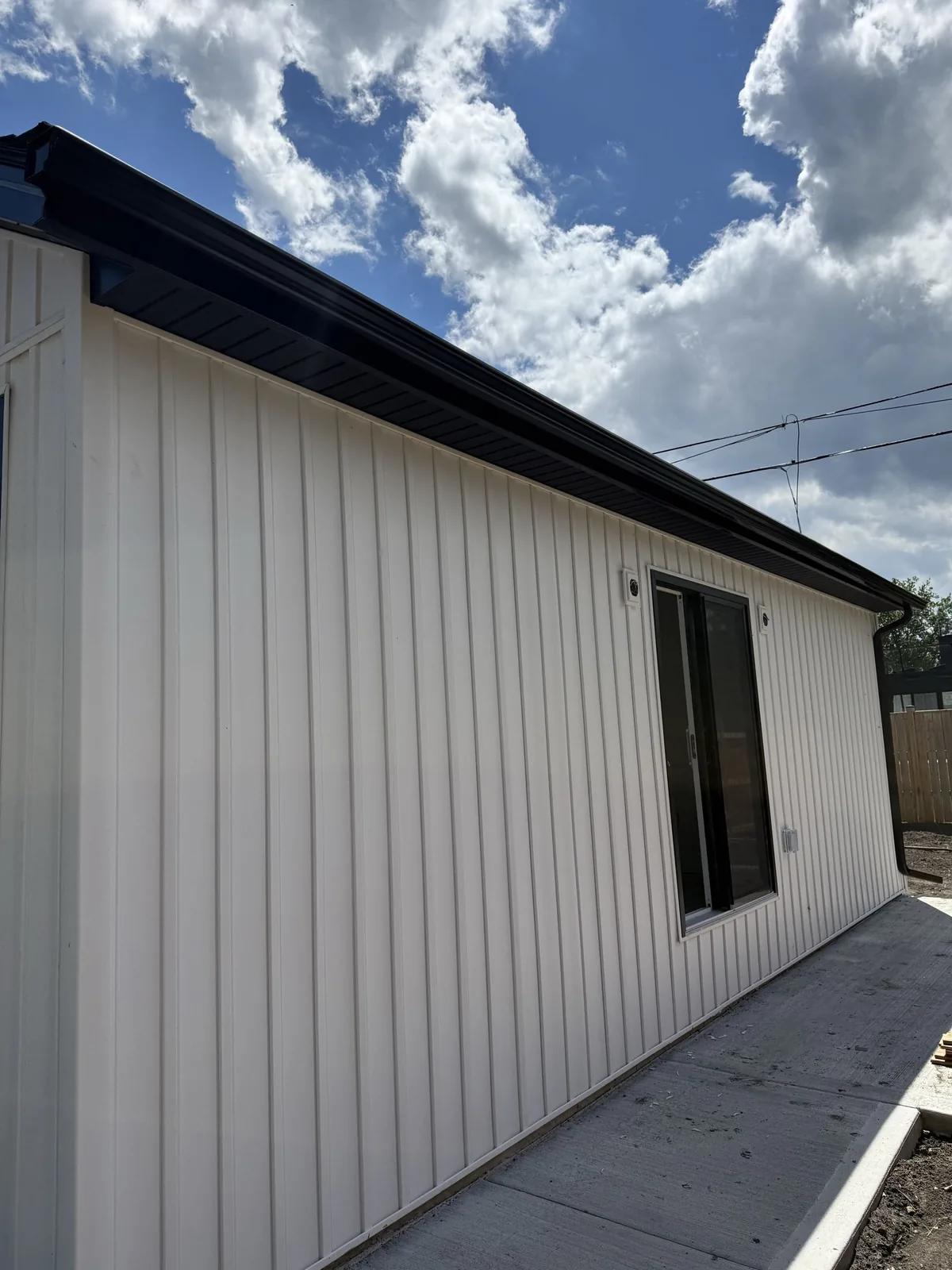 White vertical siding below a dark eavestrough and soffit