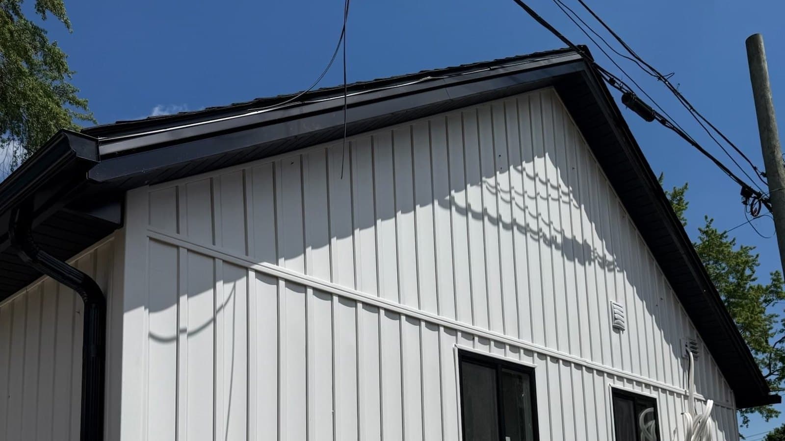 White vertical siding with dark roofline trim