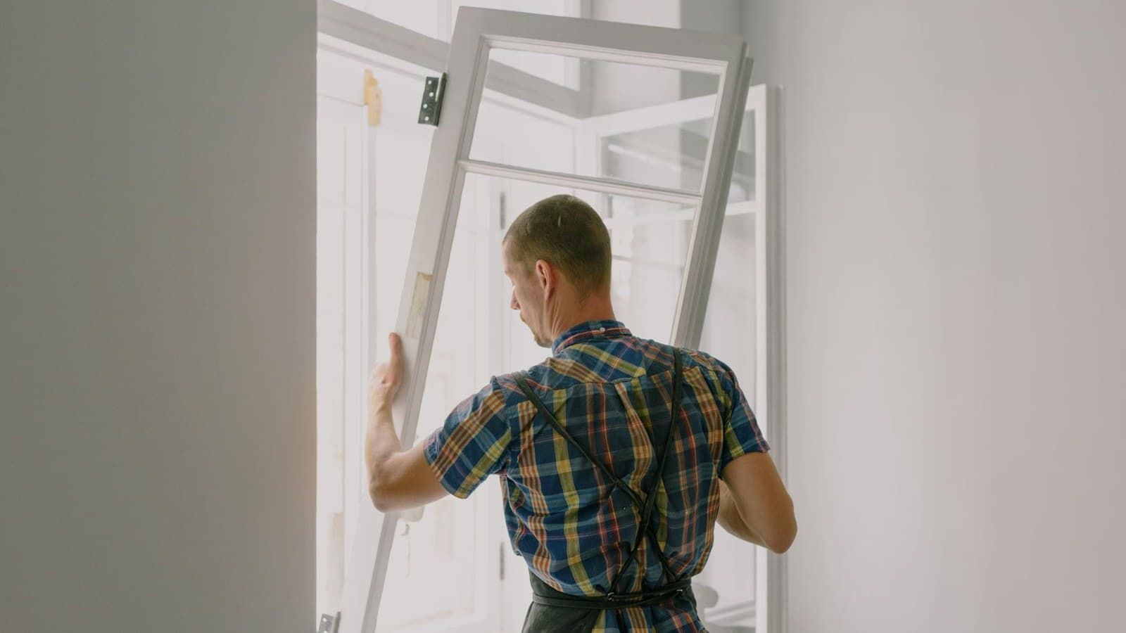 Installer positioning a white-framed replacement window